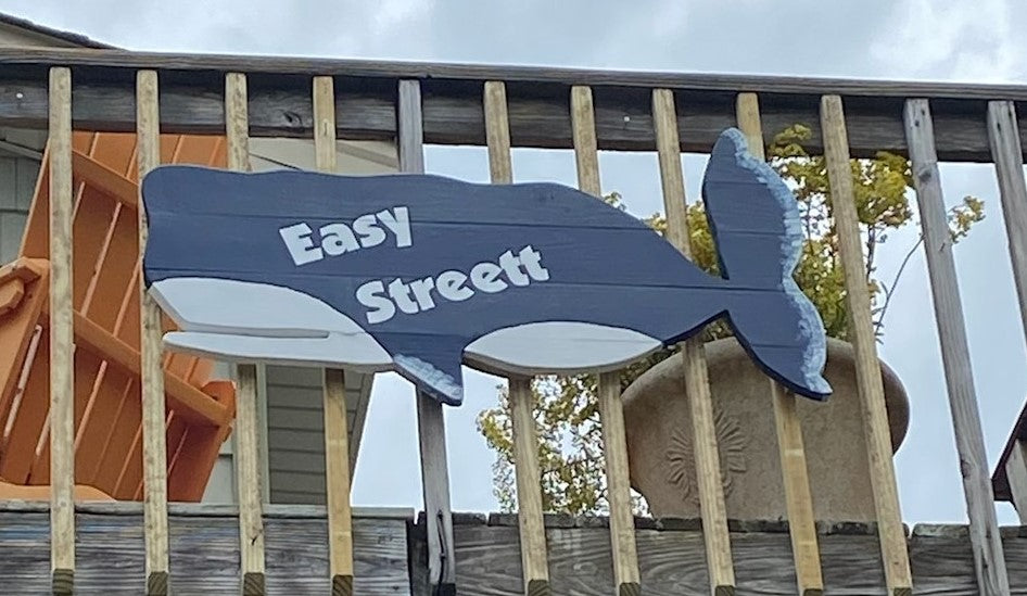A blue and white whale-shaped cottage sign with the house name 'Easy Street' mounted on the side of the house. Marine grade paint for exterior use.