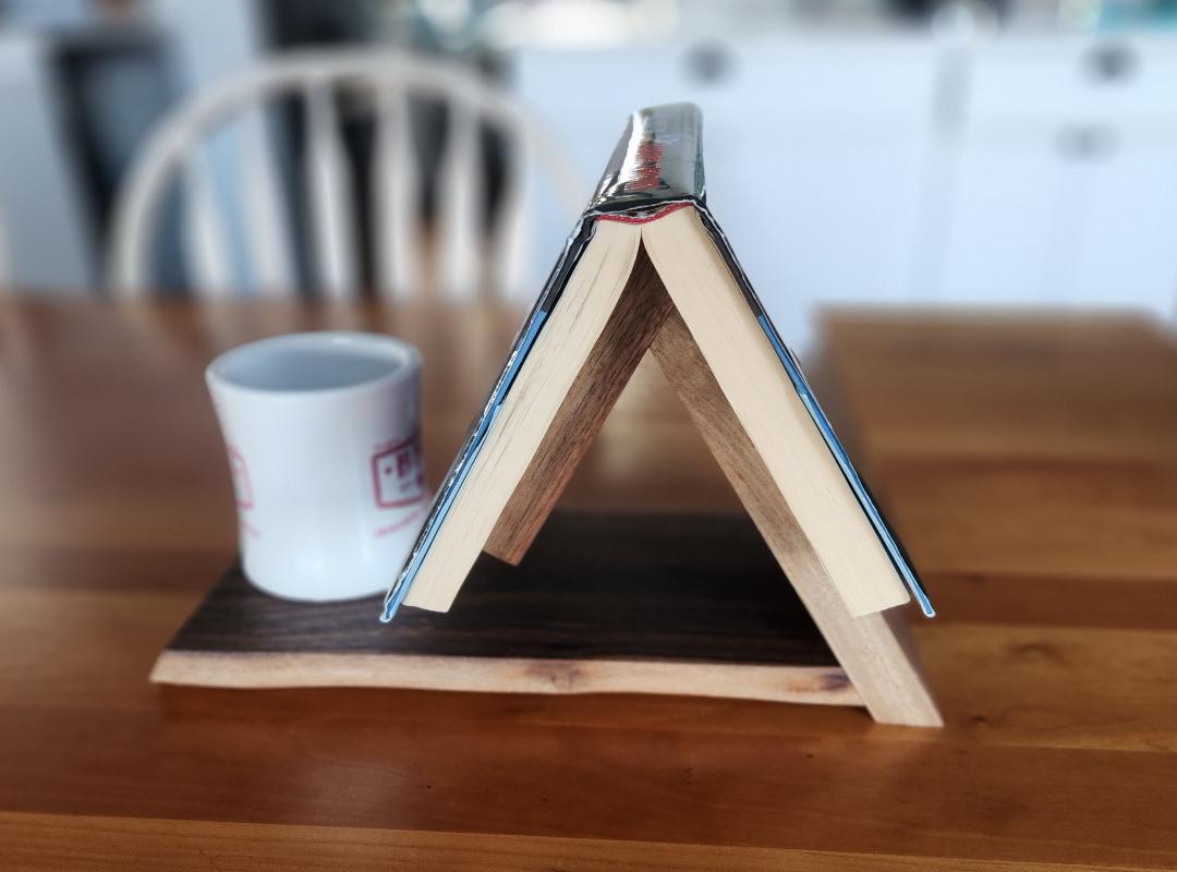 A black walnut wood book caddy with live edges, capable of holding books or magazines, and with a place for a cup or small bowl. Handcrafted